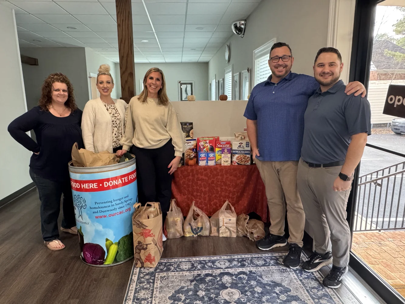 WFC Community Involvement Staff members of Wilson Family Chiropractic in Dunwoody, GA pose and smile for a photograph with food donations