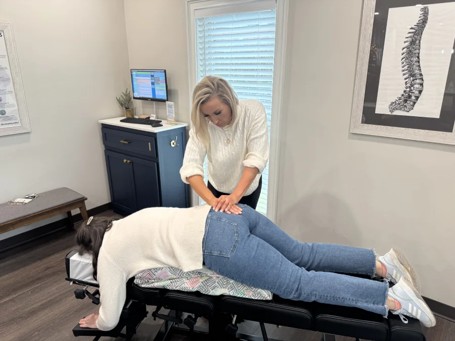 Female chiropractor performs lower back adjustment on pregnant woman while she lays on treatment table