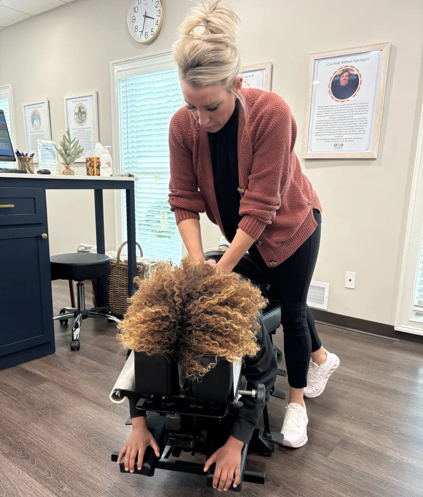 Wilson Family Chiropractic Youth Sports Adjustment Female chiropractor adjusts back of young athlete while laying on treatment table