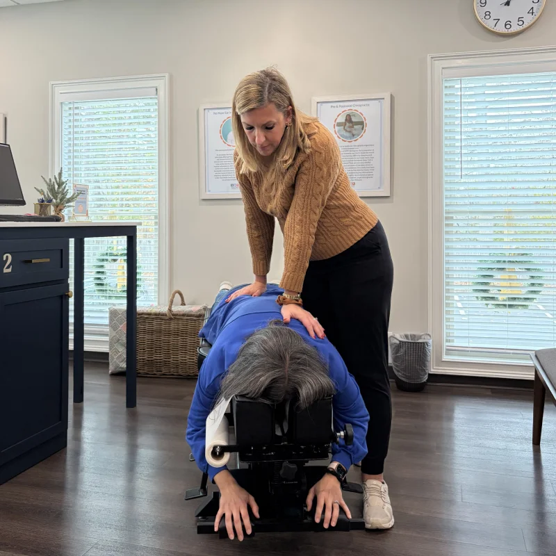 Female chiropractor performs adjustment on woman's back